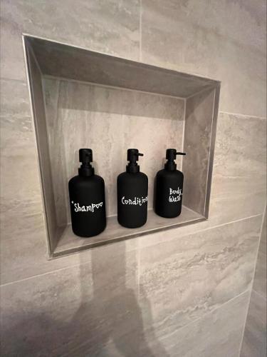 three black bottles sitting on a shelf in a bathroom at Yarra Fox Farm Cottage Farmstay in Dixons Creek