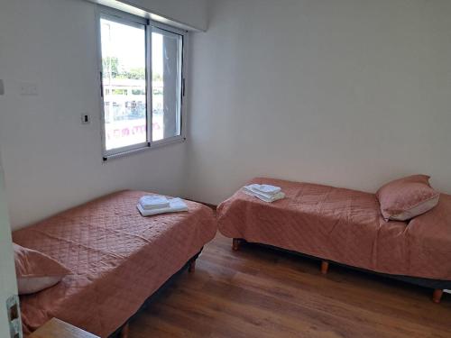 two beds and a couch in a room with a window at Departamentos 1943-2 in Villa Constitución