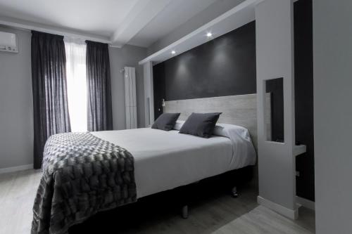 a bedroom with a large white bed with a black wall at Hostal Overnight Madrid in Madrid