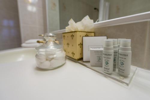 a bathroom counter with three bottles of soap and a mirror at Hotel de France in Saint Helier Jersey