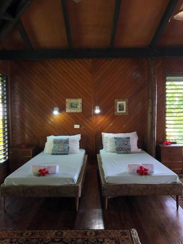 two beds in a room with wooden walls at Garden Of Eden in Matei