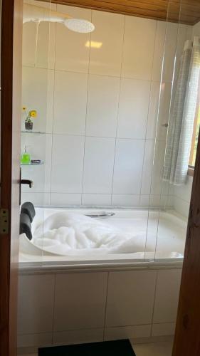 a white bath tub in a white tiled bathroom at Chalés nas Montanhas in Domingos Martins