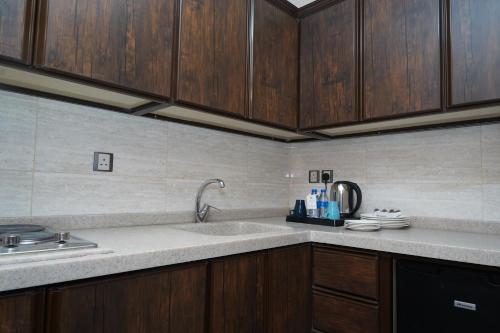 a kitchen with a sink and wooden cabinets at Roots Hotel in Makkah