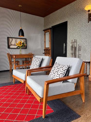 a living room with two chairs and a table at Pousada Borghetto – Charme e Exclusividade no Vale dos Vinhedos in Bento Gonçalves