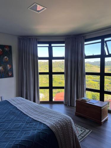 a bedroom with a bed and large windows at Pousada Borghetto – Charme e Exclusividade no Vale dos Vinhedos in Bento Gonçalves