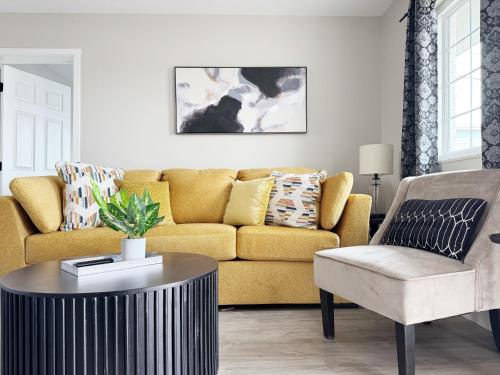 a living room with a yellow couch and a coffee table at RiverStone Retreat - Newburgh IN Stylish Apartments in Newburgh