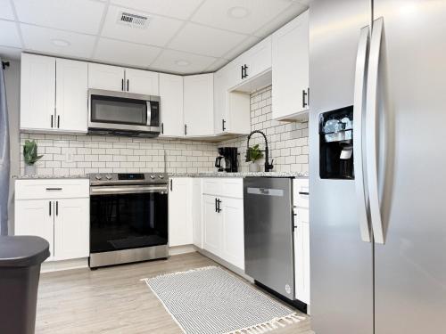 a kitchen with white cabinets and a stainless steel refrigerator at RiverStone Retreat - Newburgh IN Stylish Apartments in Newburgh