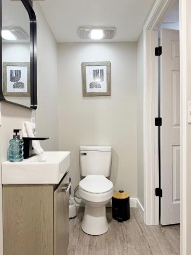 a white bathroom with a toilet and a sink at RiverStone Retreat - Newburgh IN Stylish Apartments in Newburgh