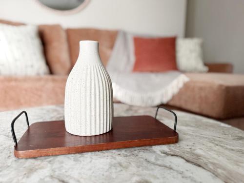 a white vase sitting on a wooden table in a living room at RiverStone Retreat - Newburgh IN Stylish Apartments in Newburgh