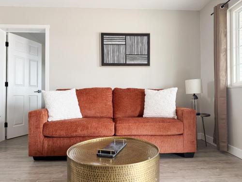 a living room with a orange couch and a table at RiverStone Retreat - Newburgh IN Stylish Apartments in Newburgh