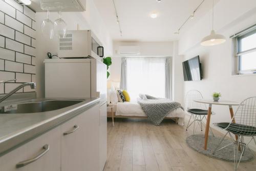 a white kitchen with a sink and a table at 5A Guest House INFINITY in Naha