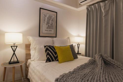 a bedroom with a bed with pillows and two lamps at 5A Guest House INFINITY in Naha