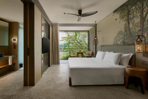 a bedroom with a large white bed and a balcony at Mandai Rainforest Resort by Banyan Tree in Singapore