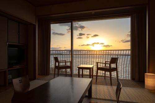 a room with a balcony with a table and chairs at KAMENOI HOTEL Genkainada in Kitakyushu