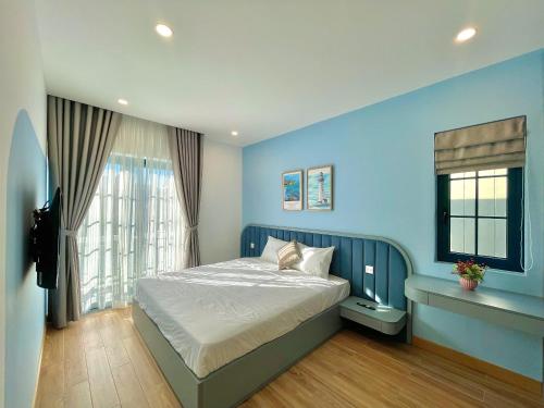 a blue bedroom with a bed and a window at Villa Novaworld Phan Thiết in Bình Tú