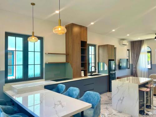a kitchen with blue chairs and a counter top at Villa Novaworld Phan Thiết in Bình Tú