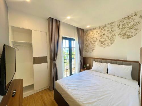 a bedroom with a white bed and a window at Villa Novaworld Phan Thiết in Bình Tú
