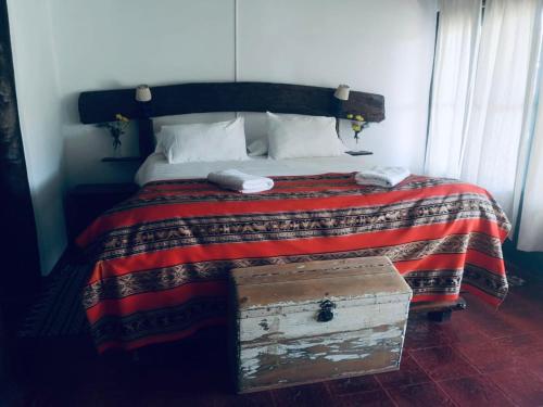 a bed with a red and white blanket and a chest at Estancia San Pablo in Tupungato