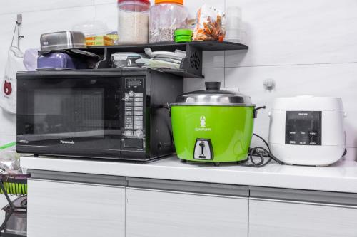 a microwave on a kitchen counter with a green pot at 25Inn Hengchun Kenting in Nanwan