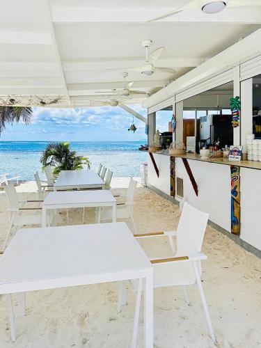 a restaurant on the beach with white tables and chairs at Pension Irivai appartement "Uparu" 1 chambre bord de mer in Uturoa