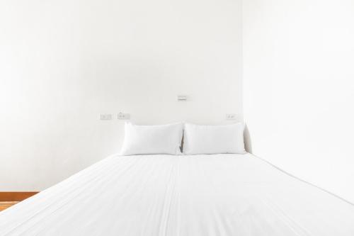 a bed with white sheets and pillows at 25Inn Hengchun Kenting in Nanwan