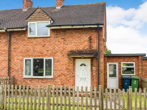 a red brick house with a wooden fence at Shrewsbury Creations in Shrewsbury