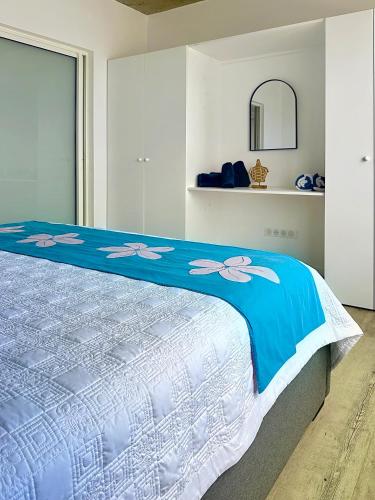 a bedroom with a bed with a blue and white comforter at Pension Irivai, appartement UO UO 3 chambres vue mer in Uturoa