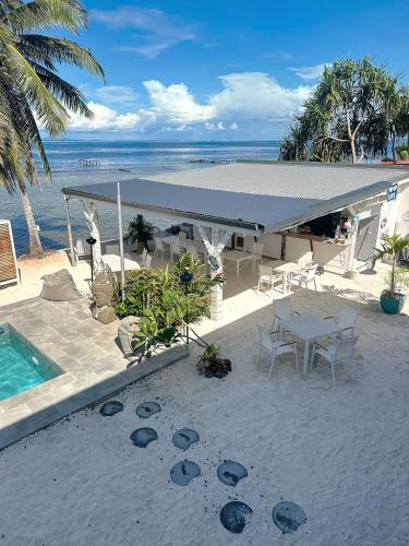 a table and chairs on the beach next to a pool at Pension Irivai, appartement UO UO 3 chambres vue mer in Uturoa