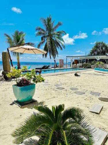a sandy beach with an umbrella and a pool at Pension Irivai, appartement UO UO 3 chambres vue mer in Uturoa