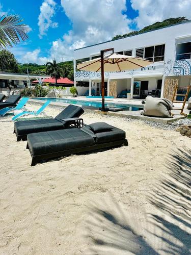 a pool with chaise lounges on the beach near a building at Pension Irivai, appartement UO UO 3 chambres vue mer in Uturoa