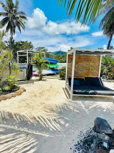 a hammock on a sandy beach next to a boat at Pension Irivai, appartement UO UO 3 chambres vue mer in Uturoa