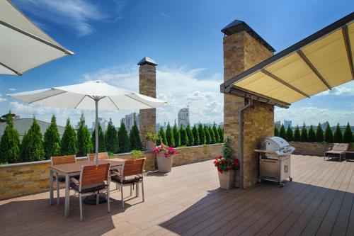 a patio with a table and an umbrella and a grill at Cityhotel Apartments in Kyiv