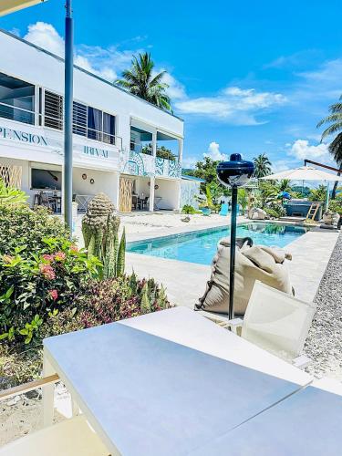 a white house with a table and a pool at Pension Irivai appartement PUATOU 1 chambre bord de mer in Uturoa
