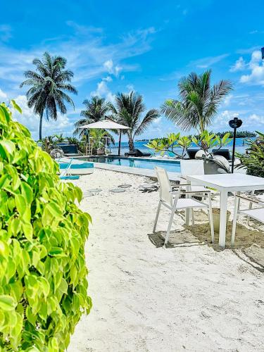 a white table and chairs on the beach next to a pool at Pension Irivai appartement PUATOU 1 chambre bord de mer in Uturoa