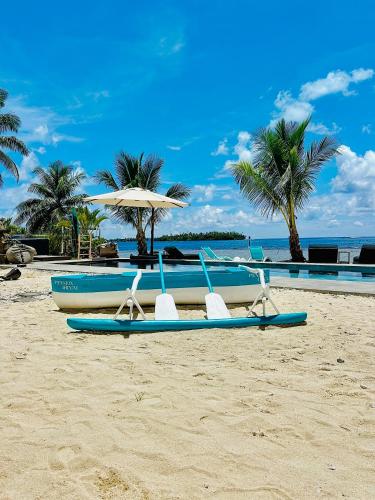 two blue surfboards and an umbrella on a beach at Pension Irivai appartement PUATOU 1 chambre bord de mer in Uturoa