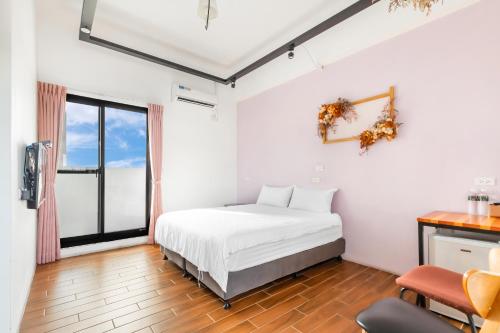 a white bedroom with a bed and a desk at 25Inn Hengchun Kenting in Nanwan