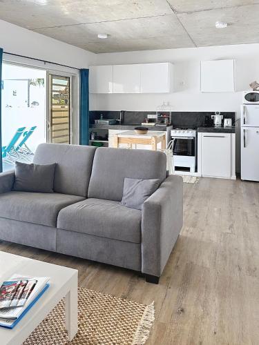 a living room with a couch and a kitchen at Pension Irivai appartement PUATOU 1 chambre bord de mer in Uturoa