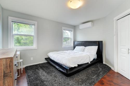 a bedroom with a bed with a black headboard and two windows at Modern Home in Victoria, BC in Victoria