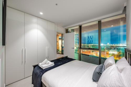 a bedroom with a white bed and a large window at Unwind with Beautiful Park & Bay Views in Melbourne