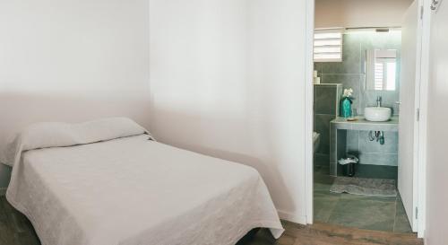a bedroom with a bed and a bathroom with a sink at Pension Irivai, Appartement RAVA 1 chambre bord de mer in Uturoa