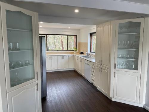 a large kitchen with white cabinets and a window at Waterfront Paradise with Jetty, BBQ, Pool table, & more in Dora Creek