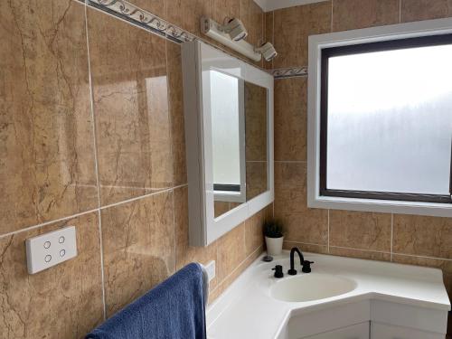 a bathroom with a sink and a mirror at Waterfront Paradise with Jetty, BBQ, Pool table, & more in Dora Creek
