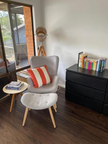 a chair with a pillow sitting next to a dresser at Waterfront Paradise with Jetty, BBQ, Pool table, & more in Dora Creek