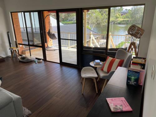 a living room with a table and chairs and a balcony at Waterfront Paradise with Jetty, BBQ, Pool table, & more in Dora Creek