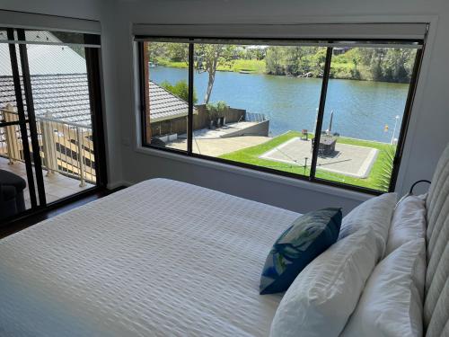 a bedroom with a bed and a large window at Waterfront Paradise with Jetty, BBQ, Pool table, & more in Dora Creek