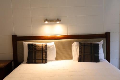 a bed with two pillows and a light above it at Bounty Motel in Paihia