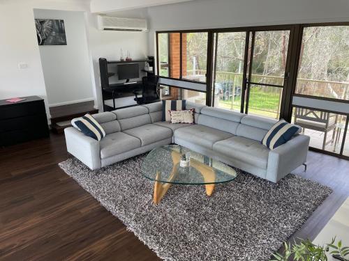 a living room with a couch and a glass table at Waterfront Paradise with Jetty, BBQ, Pool table, & more in Dora Creek