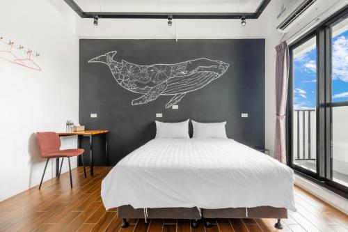 a bedroom with a bed with a whale stencil on the wall at 25Inn Hengchun Kenting in Nanwan