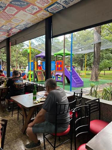 a man sitting at a table in a restaurant with a playground at Pousada São Miguel in Abadiânia