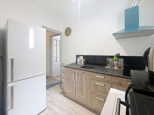 La cuisine est équipée d'un réfrigérateur blanc et de placards en bois. dans l'établissement Granville Centre: Appt 3 Chambres Proche Plage - FR-1-361-561, à Granville